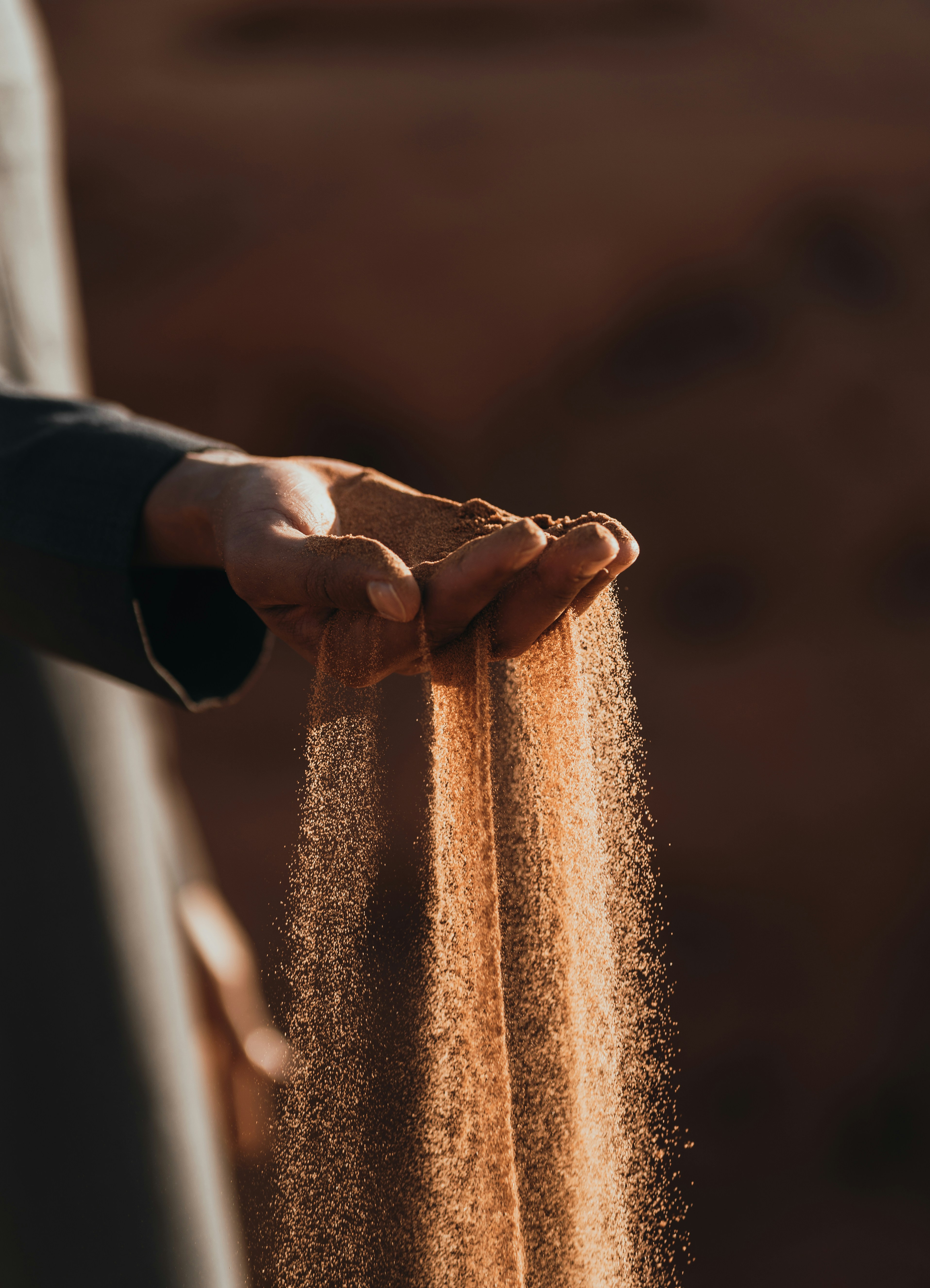 Hands letting sand fall through fingers — a tactile grounding sensory experience